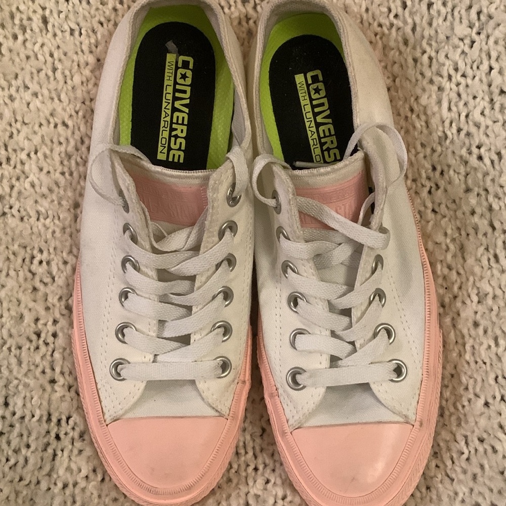 Women’s Converse white low rise sneakers with pink
toecaps and accents, size 8.